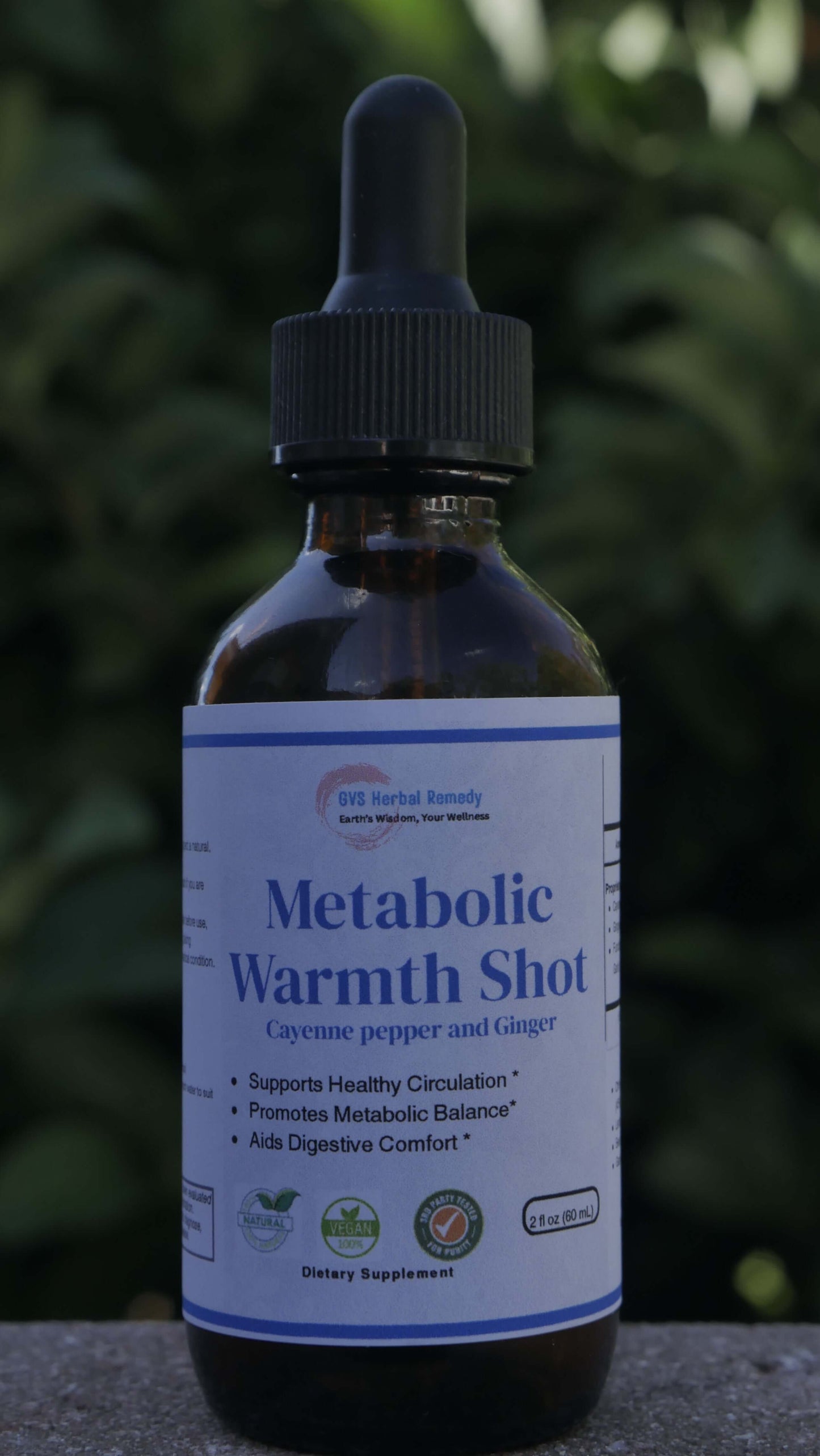 Bottle of Metabolic Warmth Shot with a dropper on a blurred green background